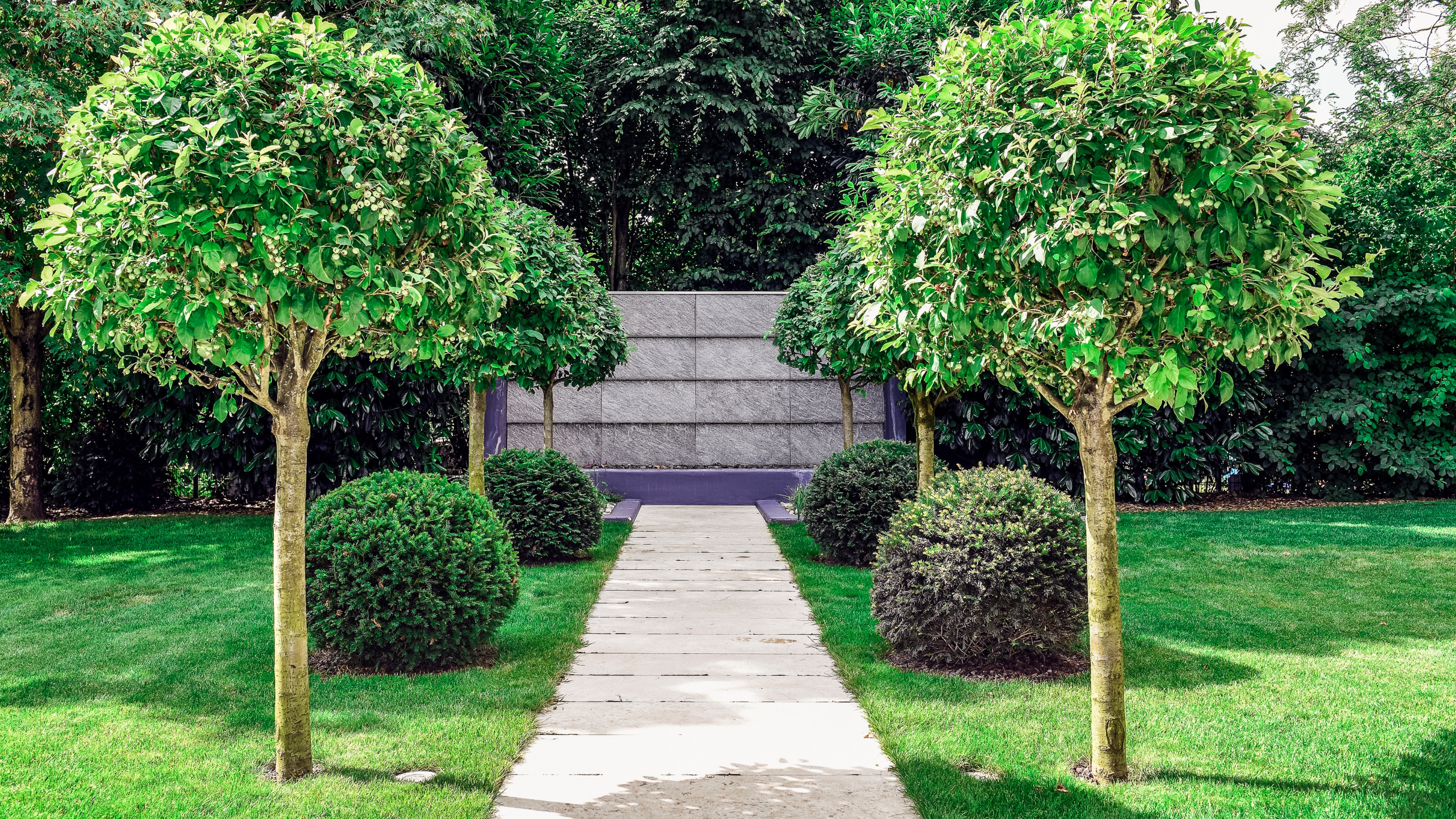 Symmetrische Aufnahme eines gepflasterten Weges, der zu einem Wasserfall führt